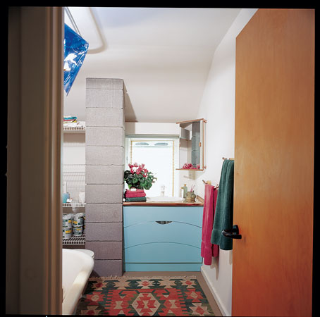 Recycled wood cabinets tinted with vibrant-hued nontoxic paint plus concrete block construction characterize this upstairs eco-bath tucked under the passive solar canopy above the garden room.